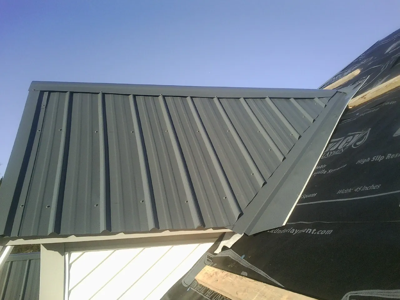 Gray metal roof panels going on over a garage gable in Union City